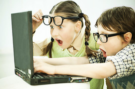 Cute boy and girl nerd looking at the laptop with surprise.